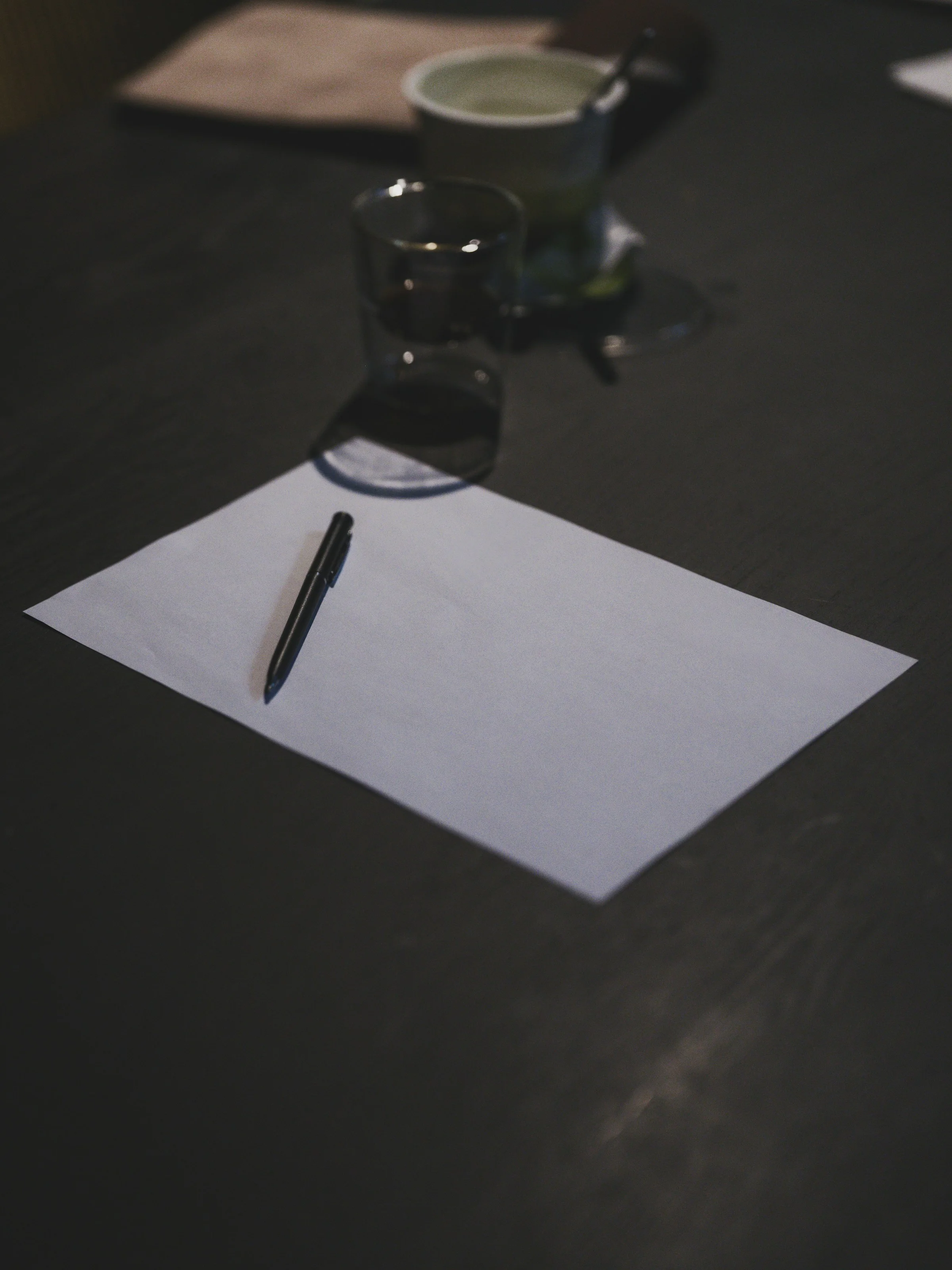 Paper and pen on a dark table for The Standard
